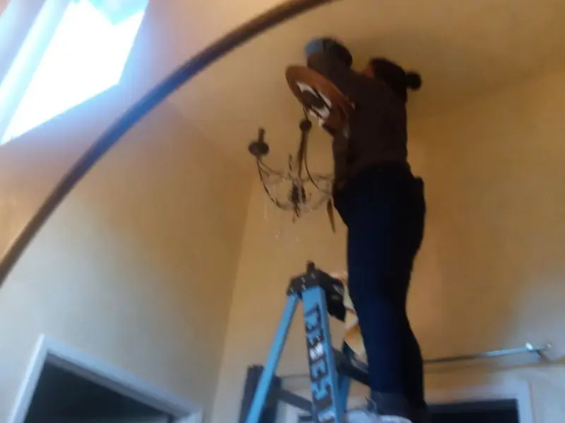 Electrician installing a chandelier in a Watertown residence